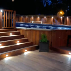 Wooden hot tub and patio area lit up at night
