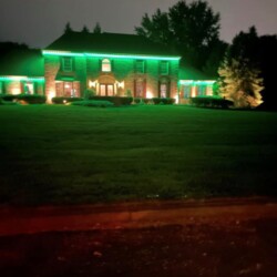 House with green holiday lighting at night